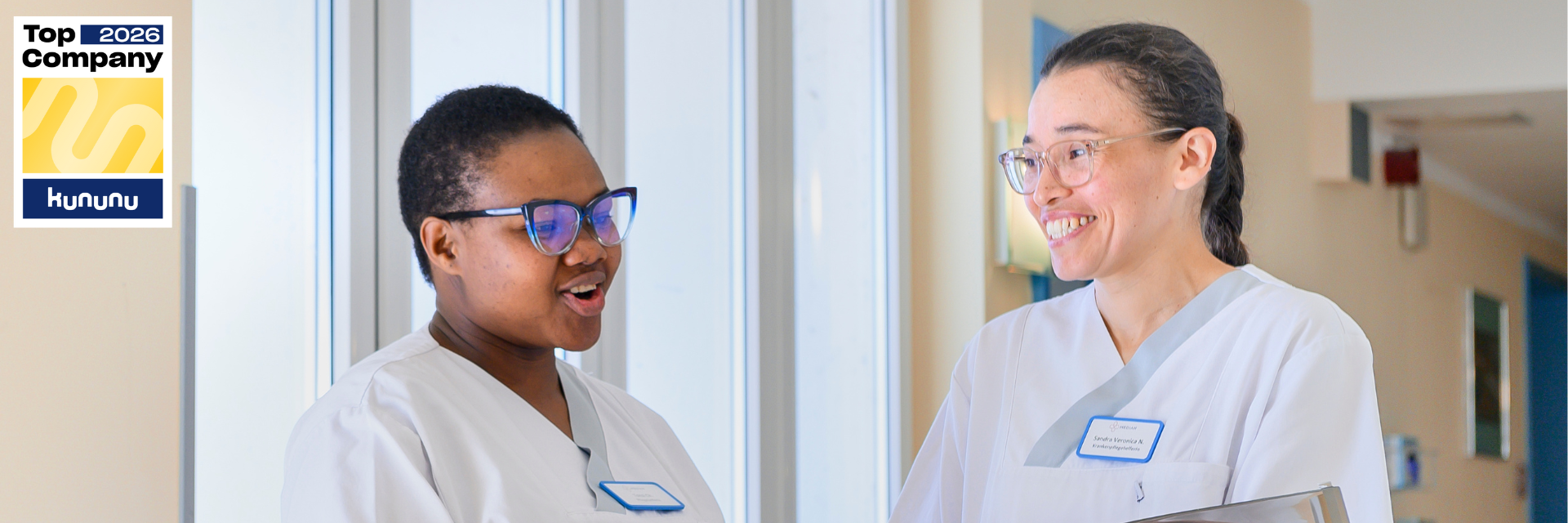 Zwei Pflegerinnen unterhalten sich und lachen