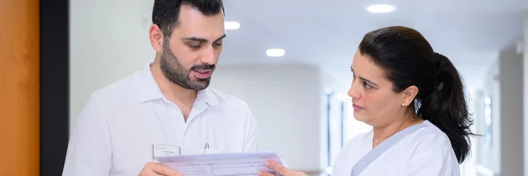 Zwei Pflegekräfte besprechen eine Patientenakte