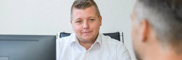 Ein Verwaltungsmitarbeiter im Gespräch mit einem Patienten
