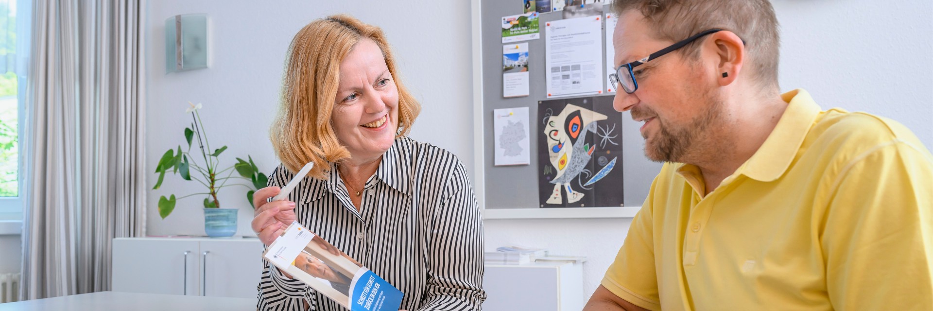 Eine Mitarbeiterin des Sozialen Dienstes im Gespräch mit einem Patienten