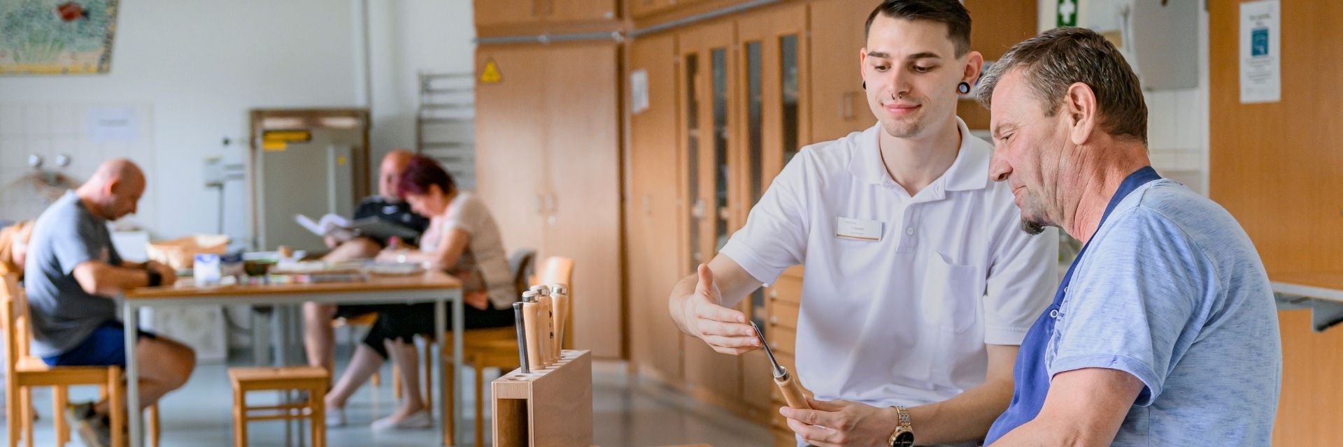 Ein Ergotherapeut erklärt einem Patienten den Umgang mit einer Feile