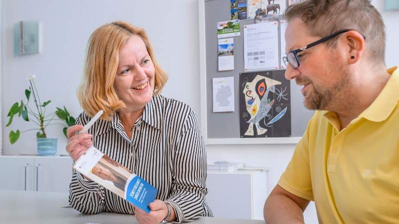 Eine Mitarbeiterin des Sozialen Dienstes im Gespräch mit einem Patienten