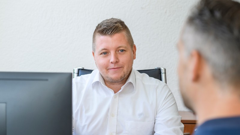 Ein Verwaltungsmitarbeiter im Gespräch mit einem Patienten